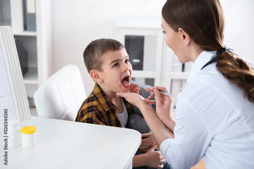 Children's doctor examining little patient's throat in clinic