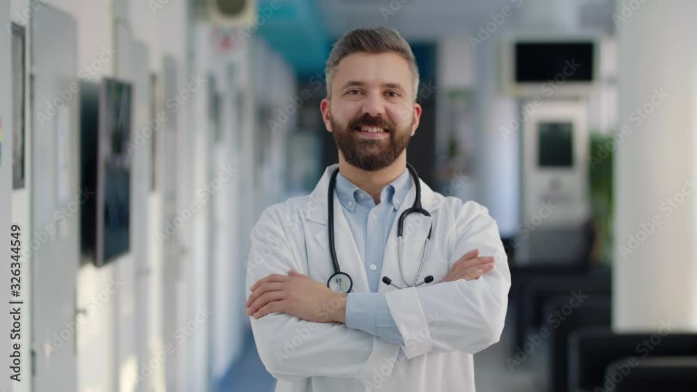 A portrait of man doctor standing in hospital, looking at camera.