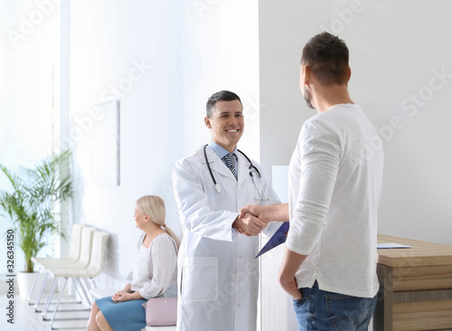 Doctor and patient shaking hands in hospital hall