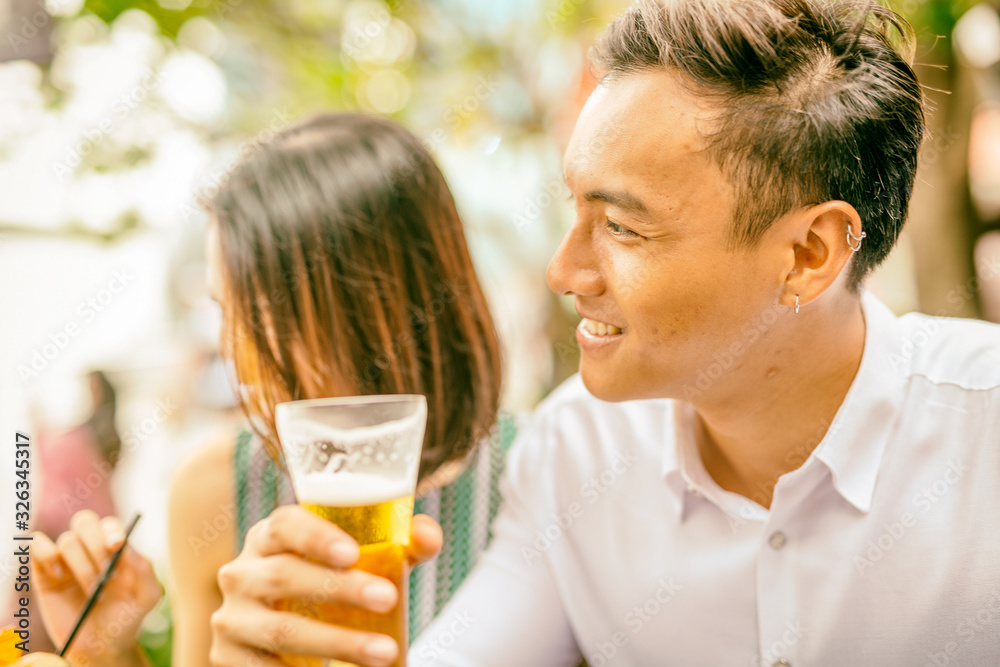 Asian young couple enjoying outdoor time together drinking at a table Asian young couple enjoying outdoor time together drinking at a table