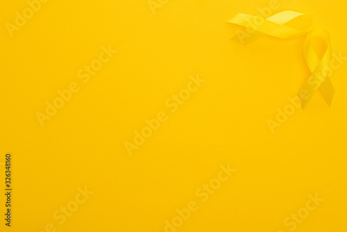 Top view of yellow awareness ribbons on bright colorful background, international childhood cancer day concept