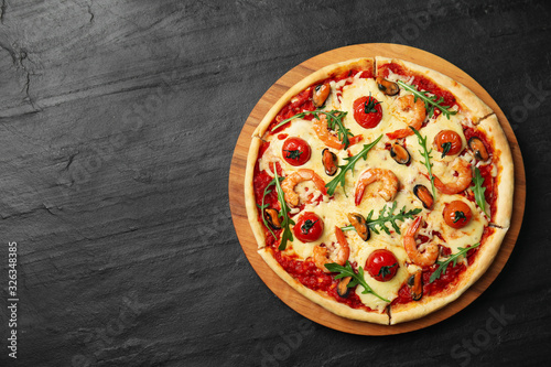 Delicious seafood pizza on black table, top view. Space for text