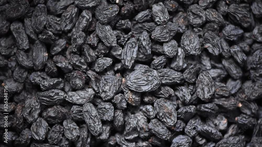 Black raisins on rotating background. Top view. Dried fruits background. Food ingredient background. Vegan, vegetarian diet. Healthy lifestyle. Fresh sweet raisin, organic food. Black raisins on rotating background. Top view. Dried fruits background. Food ingredient background. Vegan, vegetarian diet. Healthy lifestyle. Fresh sweet raisin, organic food.