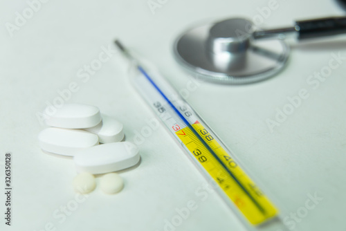Thermometer and tablets on a white background due to flu