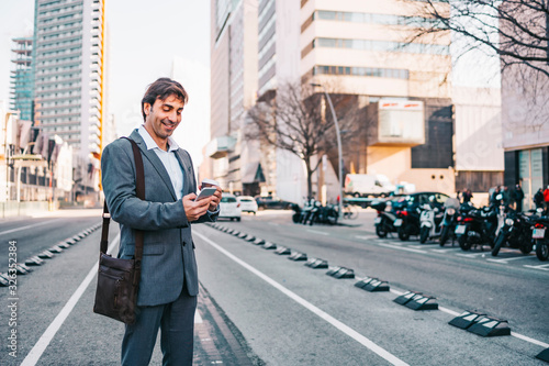 Photography Middle aged businessman using his cellphone on the city