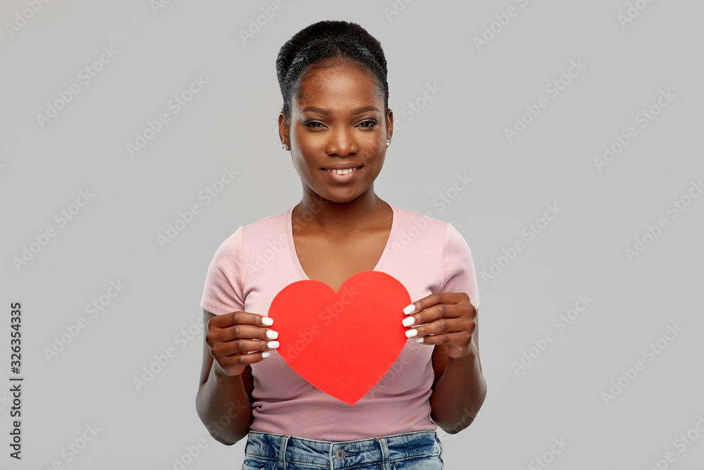 love, valentine's day and charity concept - happy african american young woman with red heart over grey background love, valentine's day and charity concept - happy african american young woman with red heart over grey background