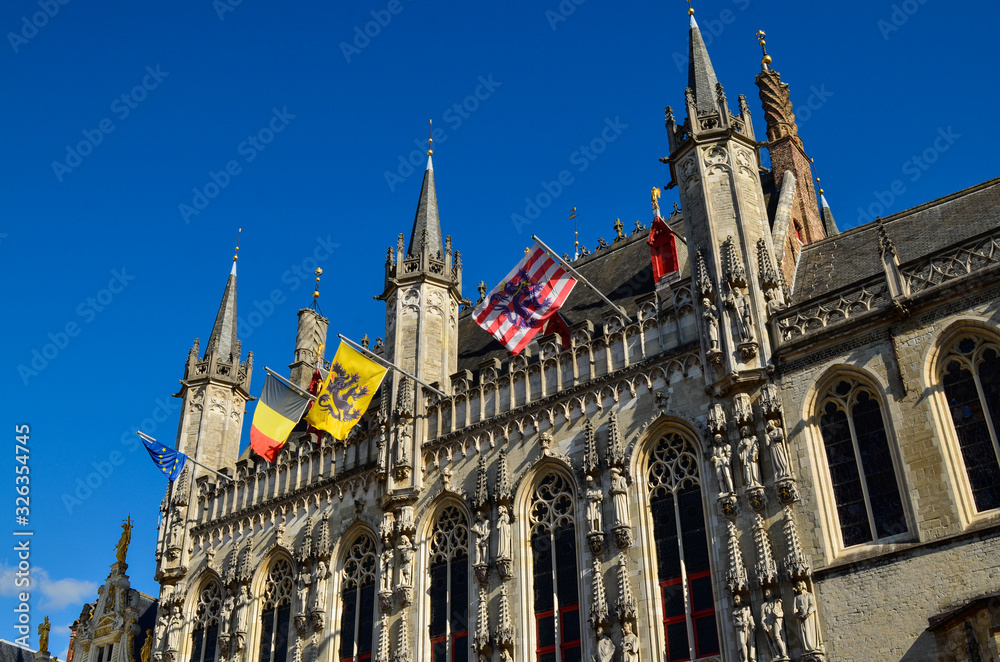 Bruges, Flanders, Belgium. August 2019. Burg square is one of the most important. The splendid town hall overlooks it. Detail of the spiers and flags that decorate the facade.
