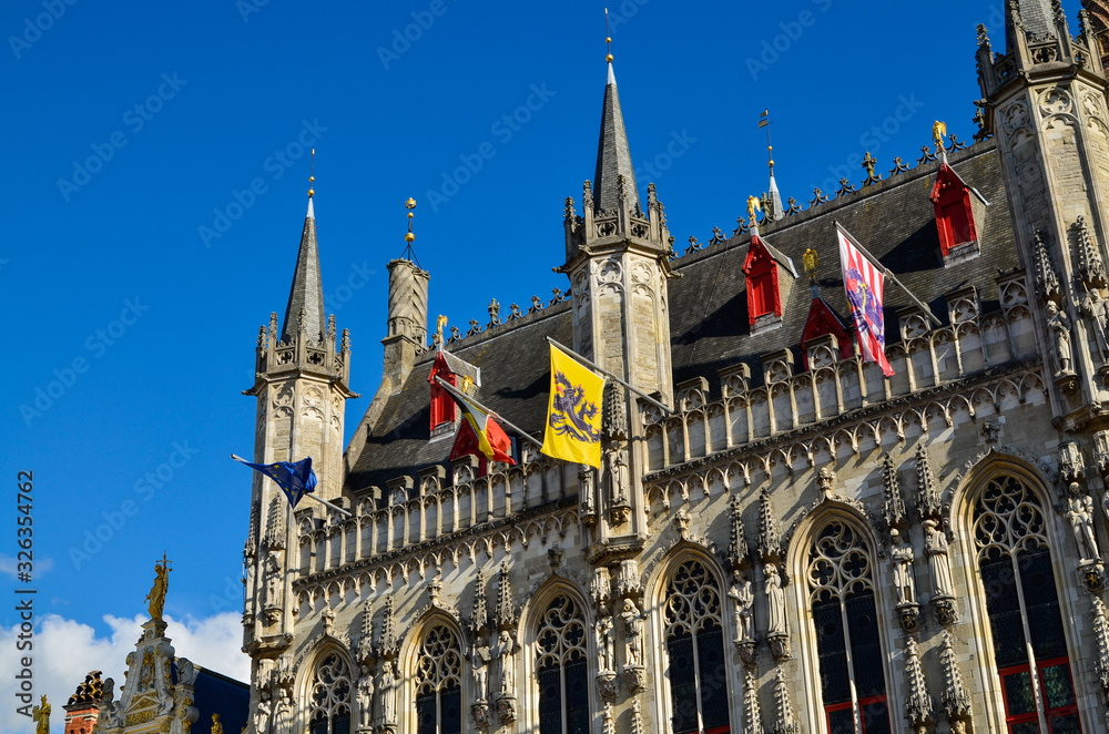 Bruges, Flanders, Belgium. August 2019. Burg square is one of the most important. The splendid town hall overlooks it. Detail of the spiers and flags that decorate the facade.
