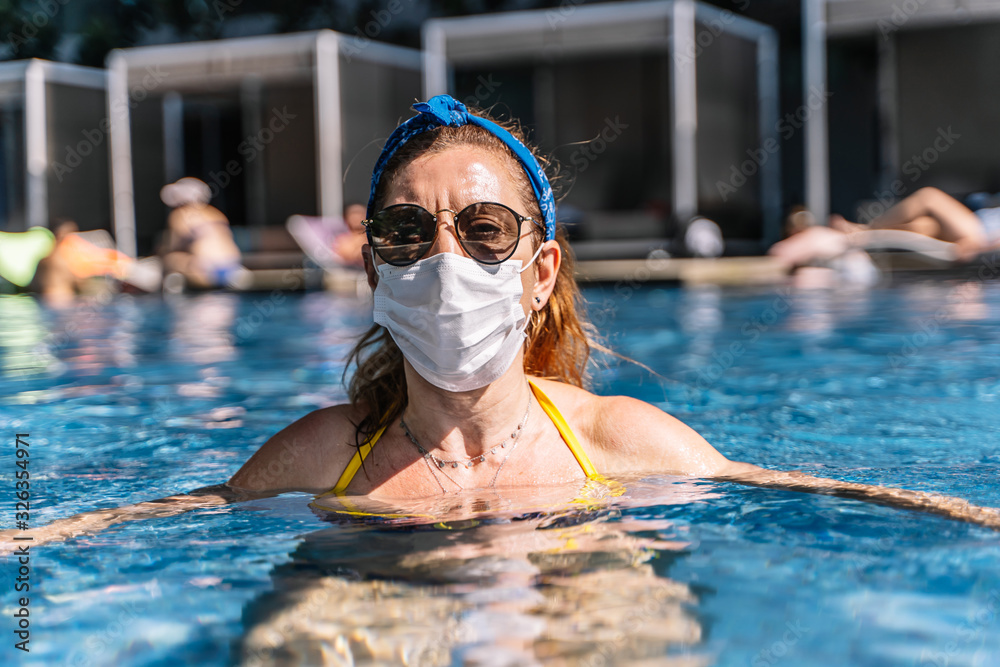 portrait of a woman tourist wearing a breathing mask in the pool for fear of coronavirus