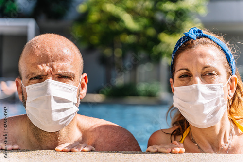 portrait of a tourist couple wearing a protective mask inside the pool for fear of the coronavirus covid19 photo