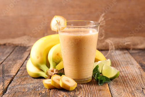 banana smoothie, fruit juice on wood background