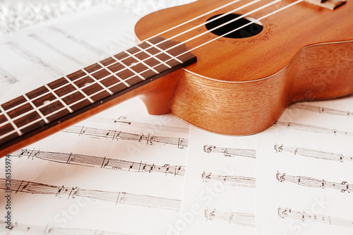High-quality beautiful Wallpaper musical wooden instrument Ukulele with white nylon strings on the background of musical notes. Lifestyle , mood toning.