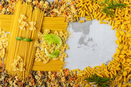 a frame of various macaroni with space for text on the right with lettuce and Basil leaves, and sprigs of dill