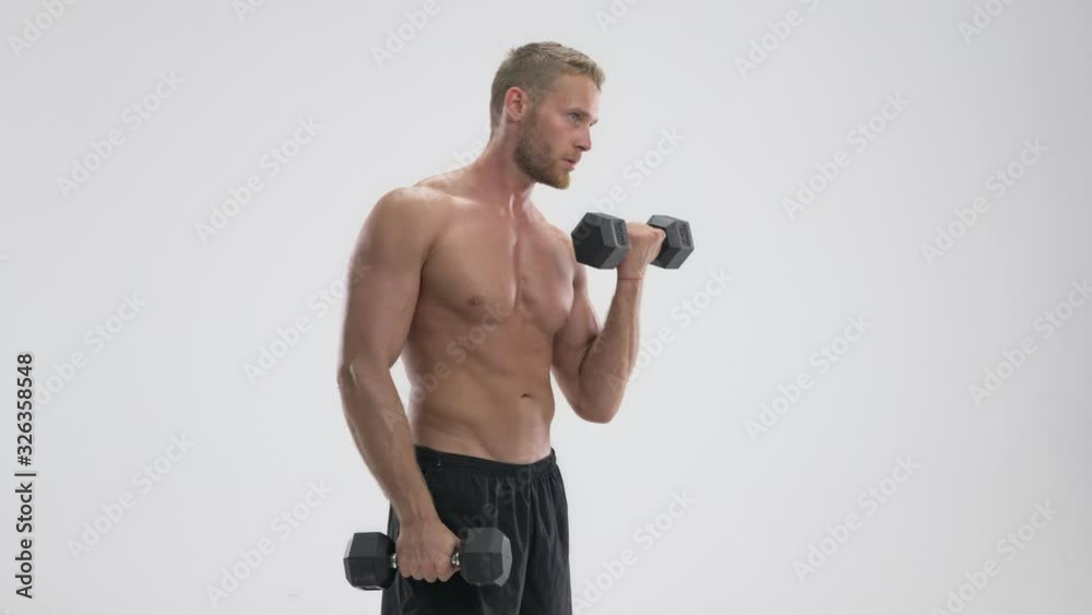 An attractive young muscular shirtless sportsman lifting heavy barbells standing isolated over white background An attractive young muscular shirtless sportsman lifting heavy barbells standing isolated over white background