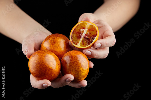 Person holging handful of half and whole red or blood oranges on black background photo