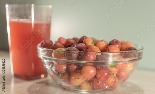 Fresh fruits and acerola juice on a wooden surface