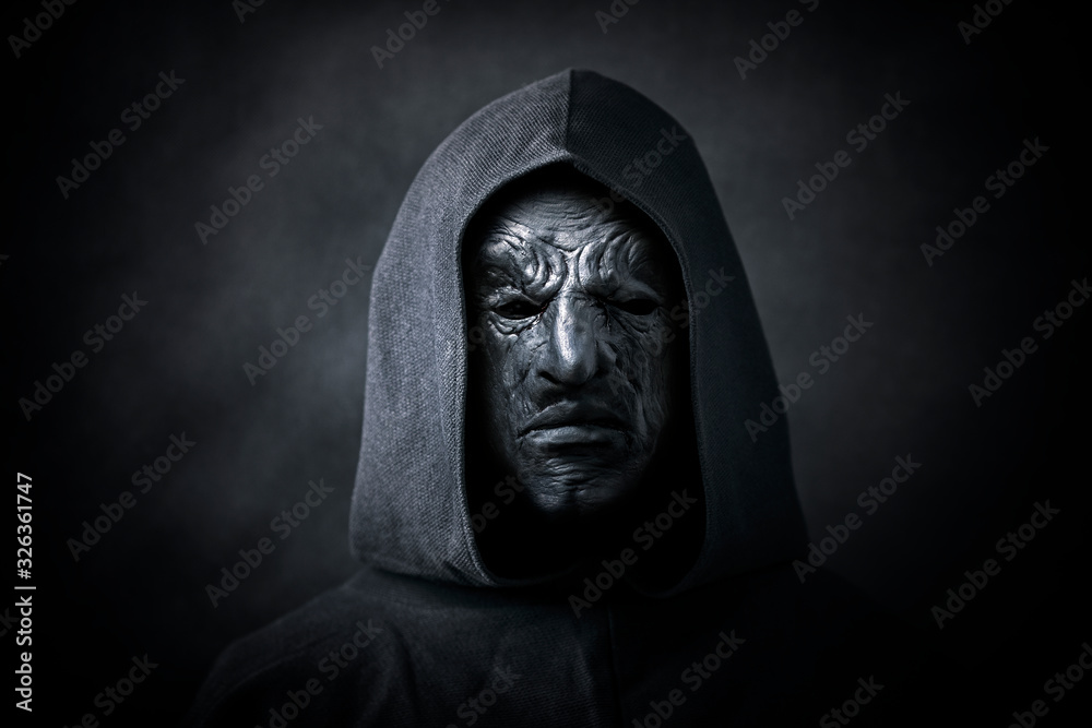 Scary figure in hooded cloak with mask