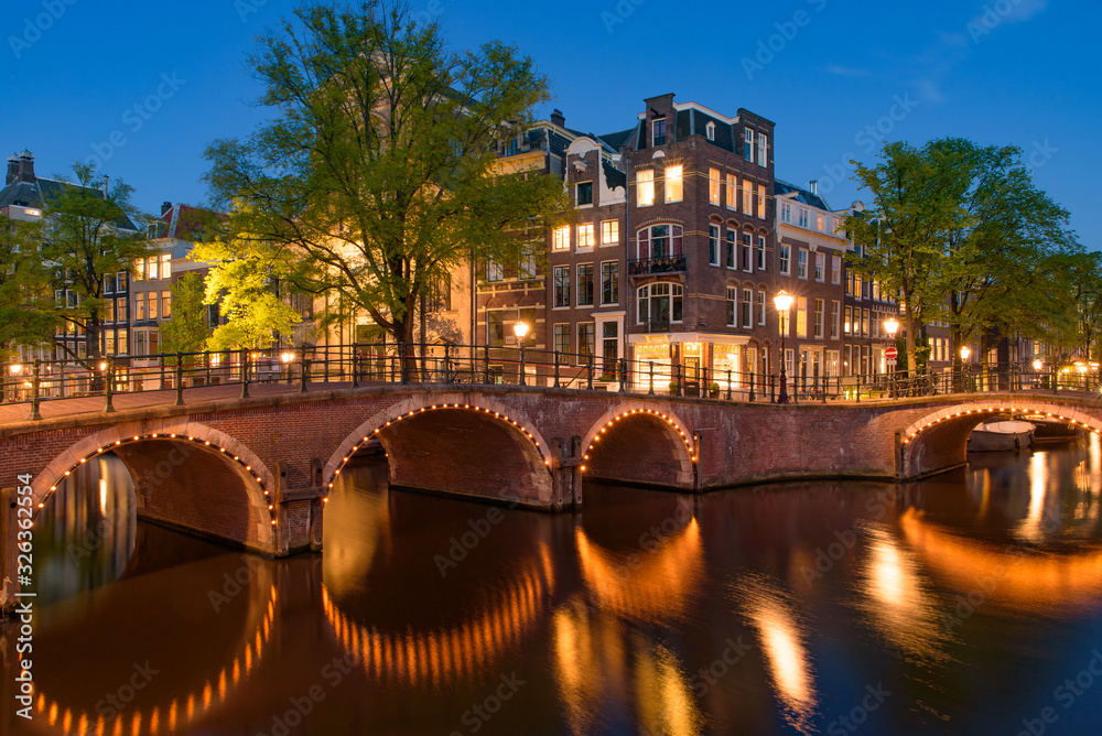 Reflection of bridge along the canal at night in Amsterdam, Netherlands
