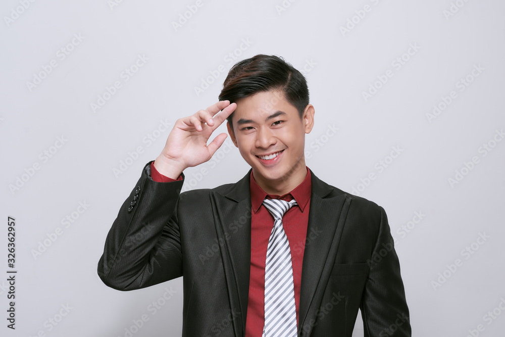 Smart casual man wearing black suit, pointing fingers to forehead standing on white background in studio Smart casual man wearing black suit, pointing fingers to forehead standing on white background in studio