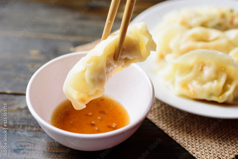 Steamed wonton dumpling stuffed with minced pork and shrimp eating with sesame oil sauce by chopsticks, Asian food Steamed wonton dumpling stuffed with minced pork and shrimp eating with sesame oil sauce by chopsticks, Asian food