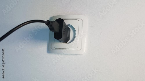 Vertical smoke escapes from USB charger of phone connected to electrical outlet