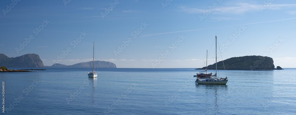 Sailboat docked in front of the beach and the port of Es Canar, Ibiza Island, Balearic islands