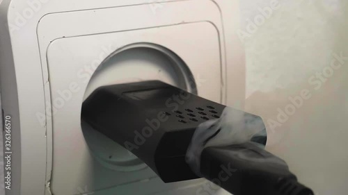 USB charger plugged into socket lights up. Electric short circuit failure Slowmo