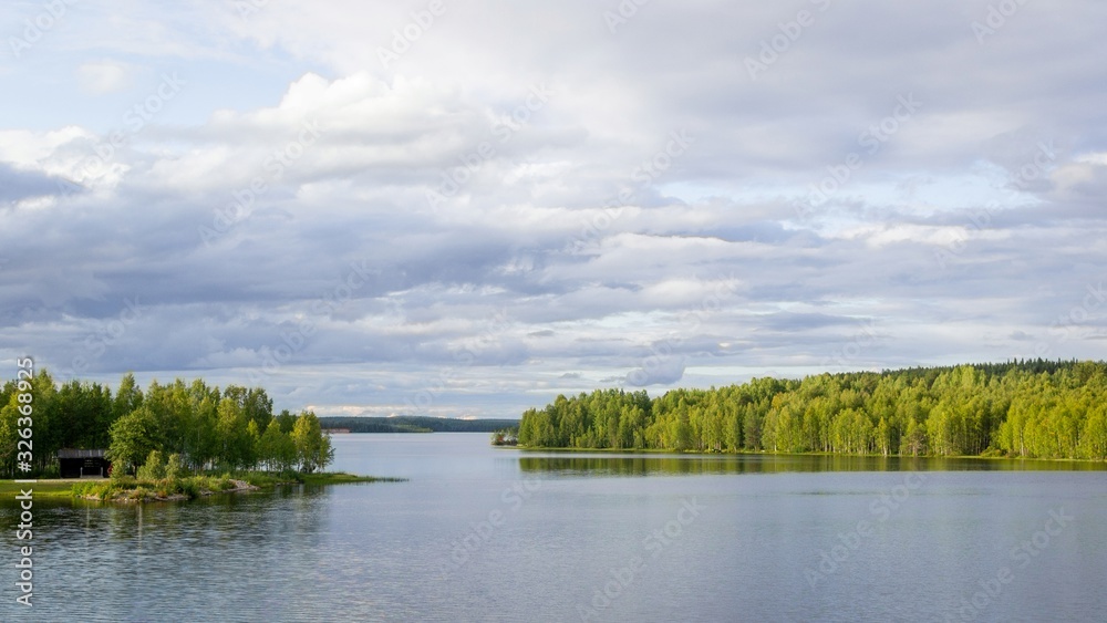 A fabulous landscape of a Finnish lake in the midst of a dense Scandinavian green forest. The concept of calm and quiet rest in the most environmentally friendly country.