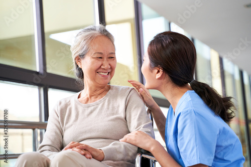 Foto friendly asian staff talking to senior resident in nursing home