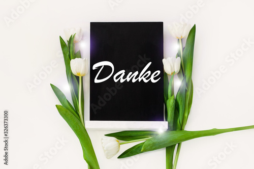 Danke thank you in German card sign on black chalkboard with tulip flowers on white background flat lay  greeting text