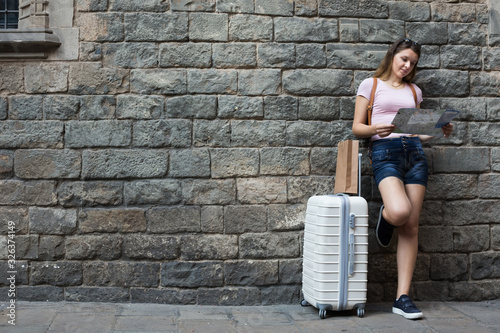 Traveling happy girl standing on wall background