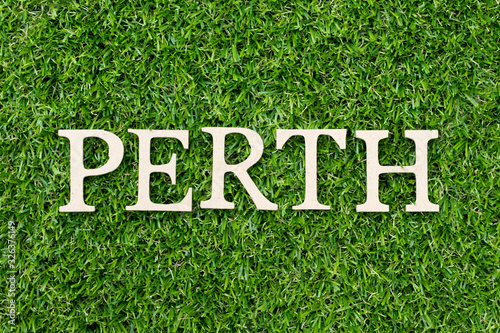 Wood alphabet letter in word Perth on green grass background