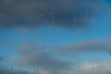Raindrops on a window and a cloudy sky during rainy weather.