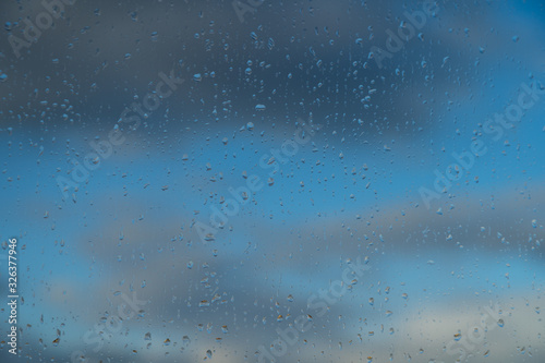 Raindrops on a window and a cloudy sky during rainy weather.