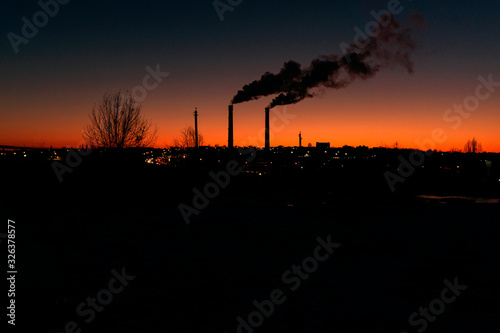 from a high pipe above the evening city a large amount of pollutants is thrown into the atmosphere from the production room