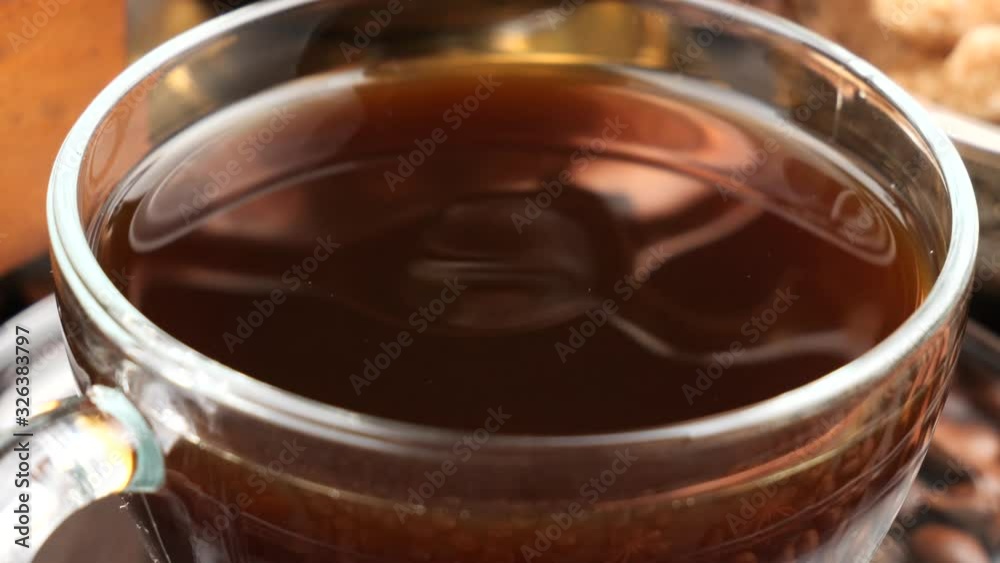 A drop of black coffee drips slowly into the coffee cup. A drop of black coffee drips slowly into the coffee cup.