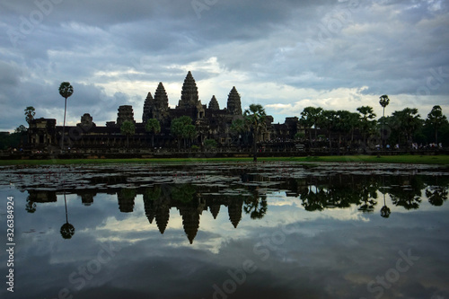Panoramic view of Angkor Wat and its mirror reflection in the lake at sunrise time. Background of cloudy sky. Cambodia © Vladimir