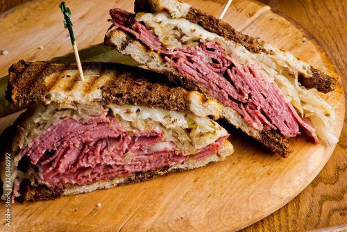 Canvas Print Reuben Sandwich, classic traditional American bar/pub menu item, on grilled rye bread, corned beef, Swiss cheese, sauerkraut and topped with thousand island dressing and french fries in background