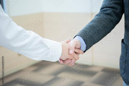 会議室で握手をするビジネスマンの手元 © west_photo