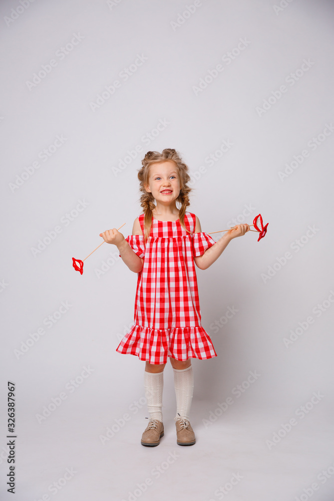 Funny smiling baby girl summer dress  on white background . Baby girl with a lip accessory on a stick.