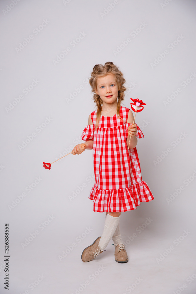 Funny smiling baby girl summer dress  on white background . Baby girl with a lip accessory on a stick.
