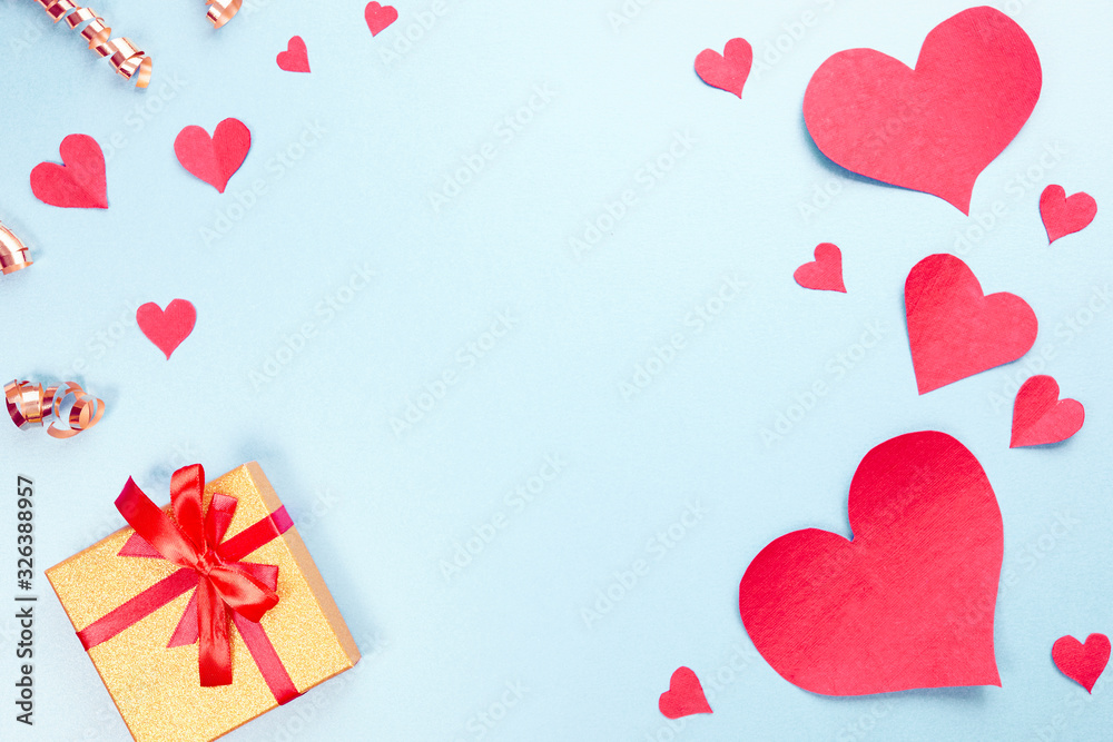 red paper hearts, gold gift, confetti on blue background. Sweet holiday background and small hearts.