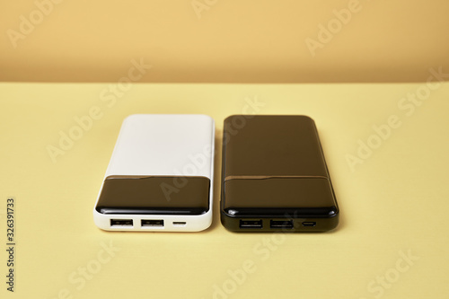 Power banks for charging mobile devices. White and black smart phone charger. External battery for mobile devices.