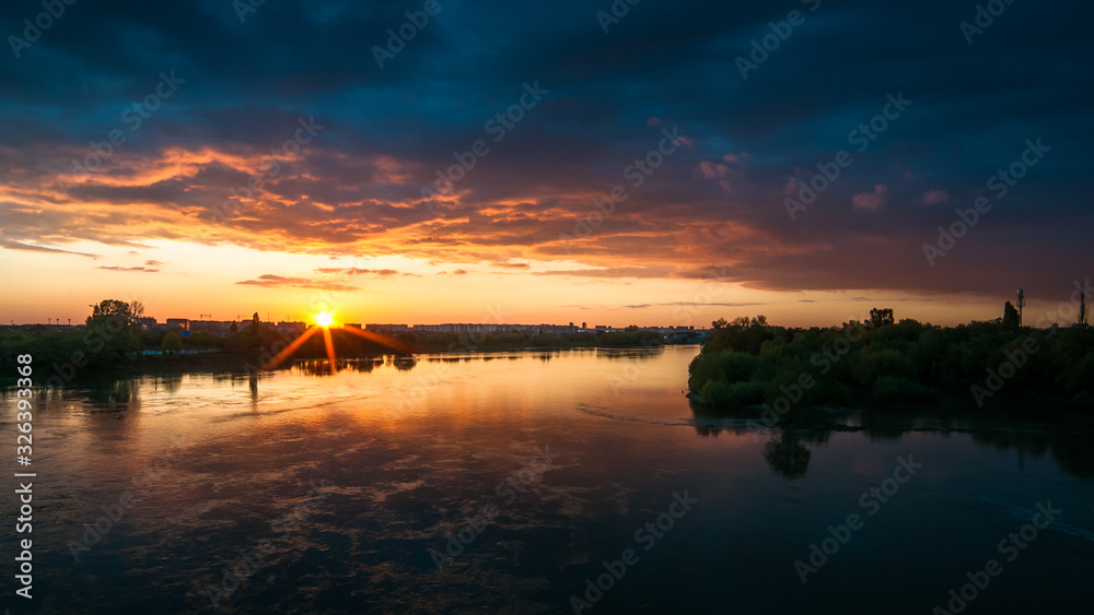 Sunset over the river in dark orange-blue tones.