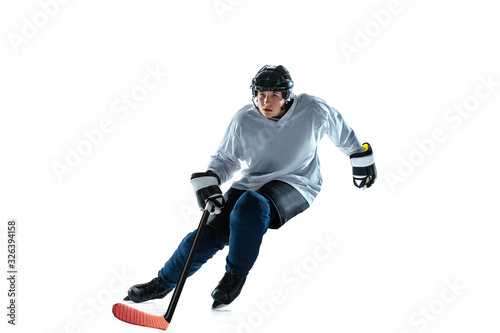Leader. Young male hockey player with the stick on ice court and white background. Sportsman wearing equipment and helmet practicing. Concept of sport, healthy lifestyle, motion, movement, action.