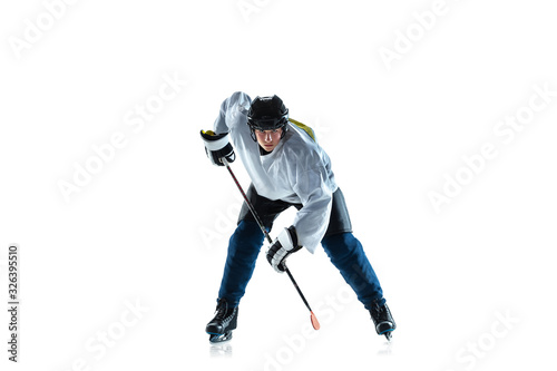 Running. Young male hockey player with the stick on ice court and white background. Sportsman wearing equipment and helmet practicing. Concept of sport, healthy lifestyle, motion, movement, action.