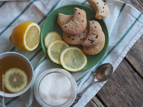 Homemade shortbread cookies sprinkled with sugar with black sesame seeds on a wooden rustic table. Tea party with cookies and lemon. Place for text. Photo for the holiday.