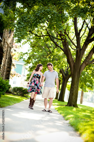 Happy Young Couple Walking on Sidewalk in Neighborhood