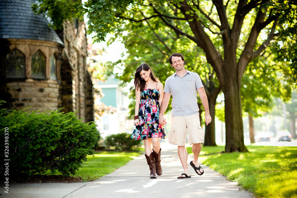 Happy Young Couple Walking on Sidewalk in Neighborhood