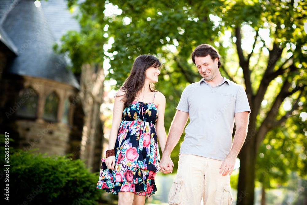 Happy Young Couple Walking on Sidewalk in Neighborhood
